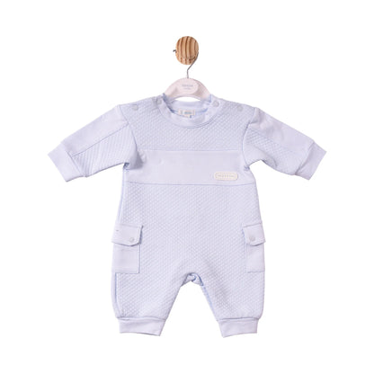A baby's short-sleeve one-piece romper in a very pale lavender-blue colour, featuring a textured waffle-weave pattern across the chest and legs, side cargo pockets, and a small oval brand patch on the chest.
