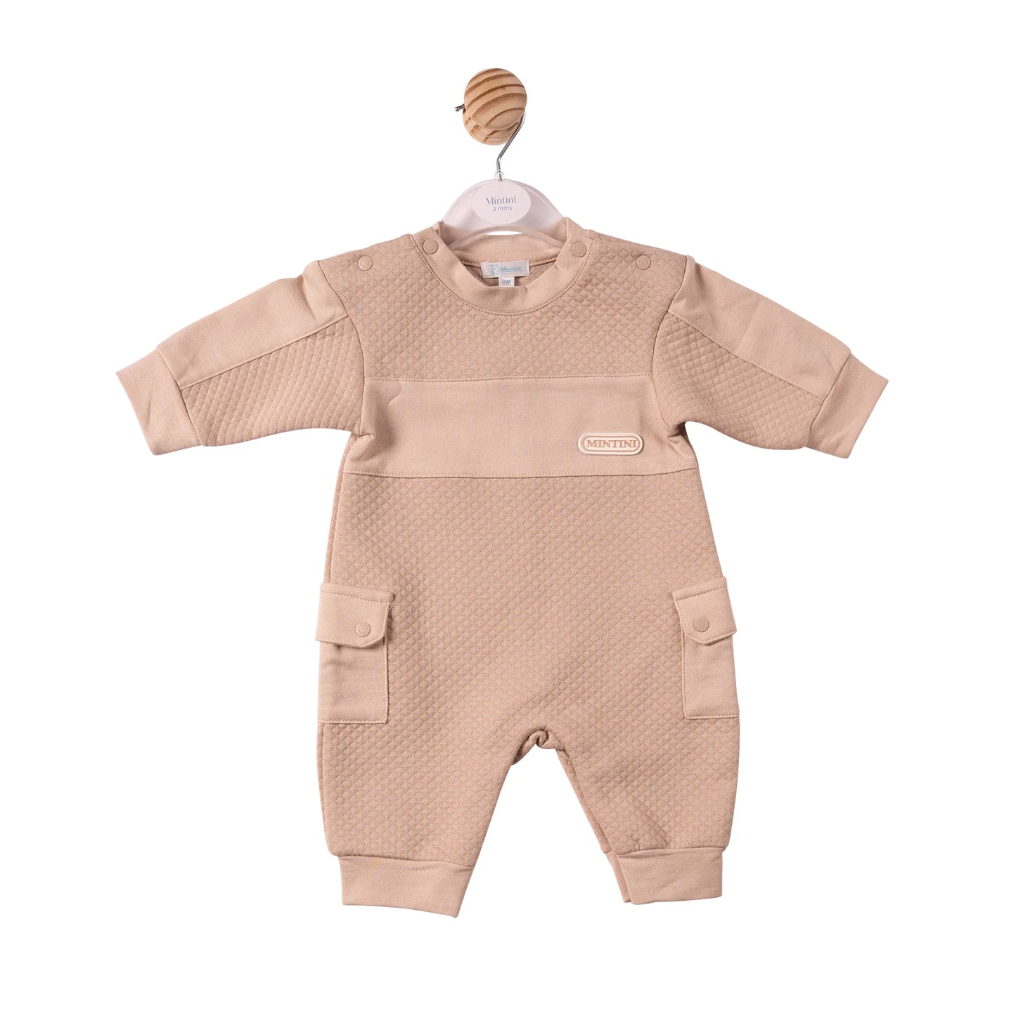 A baby's long-sleeve romper in a light beige color, featuring a textured honeycomb pattern on the chest and upper arms, a smooth solid fabric across the chest, and two front flap pockets.